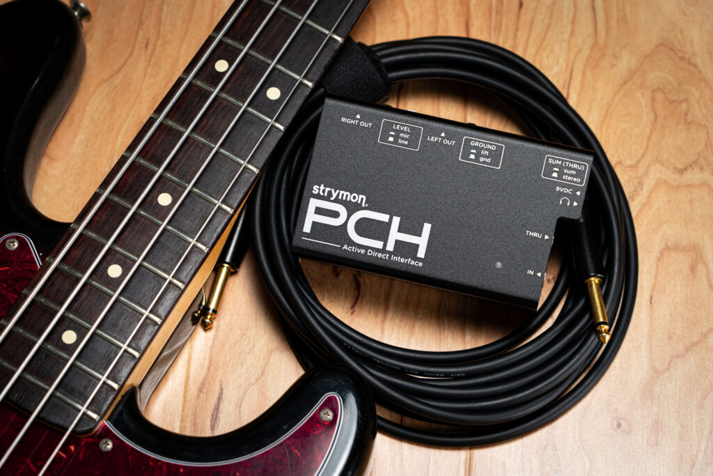 Strymon PCH sitting on top of a coiled cable next to a four string bass.
